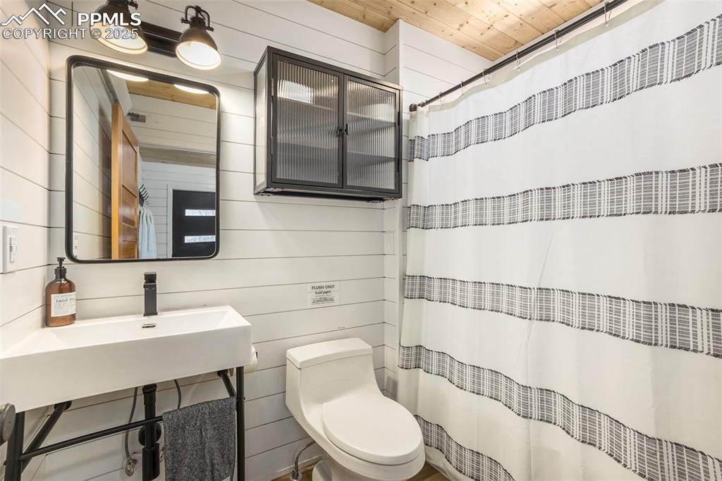 Bathroom with a shower with curtain and wood walls