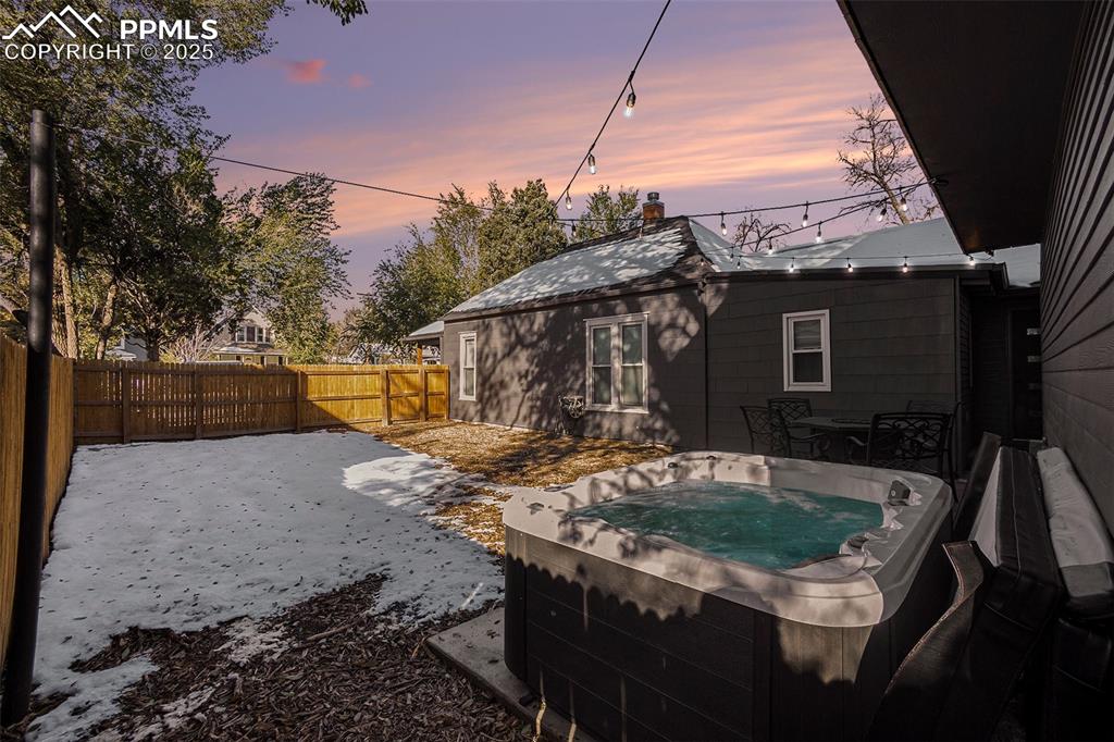 Yard at dusk featuring a hot tub, a patio, and a fenced backyard