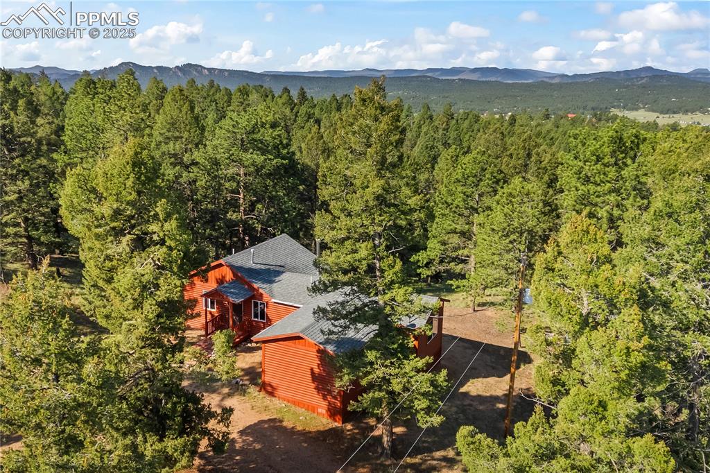 View of subject property featuring a mountainous background and a heavily wooded area