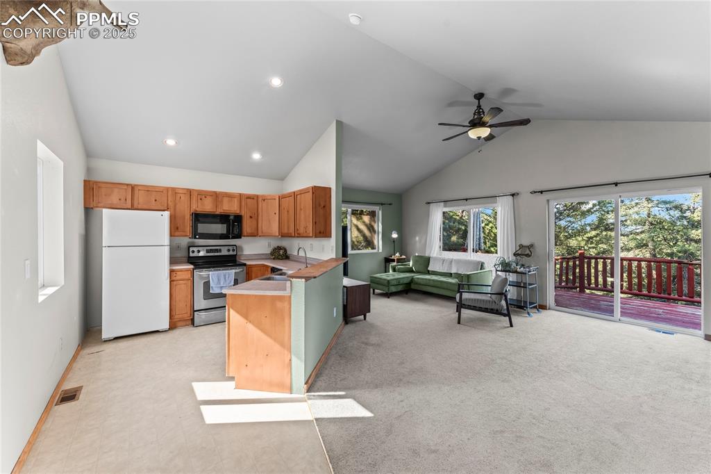 Kitchen featuring stainless steel electric range, freestanding refrigerator, black microwave