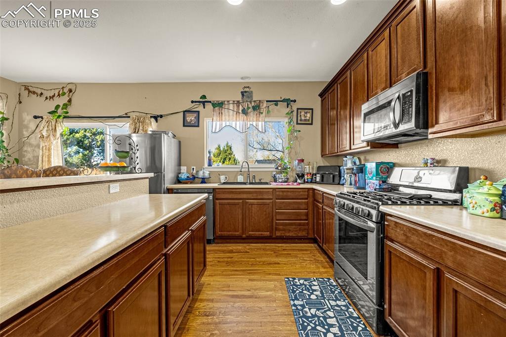 Kitchen with appliances with stainless steel finishes, light wood-style floors, light countertops, and plenty of natural light