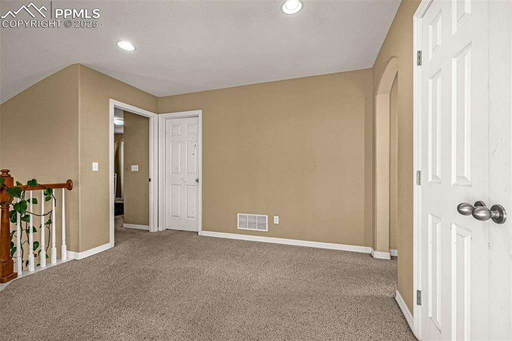 Spare room featuring arched walkways, carpet, and recessed lighting