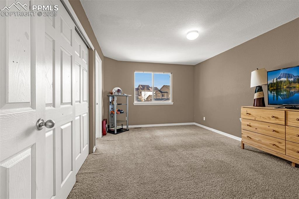 Bedroom with light colored carpet, a closet, and a textured ceiling