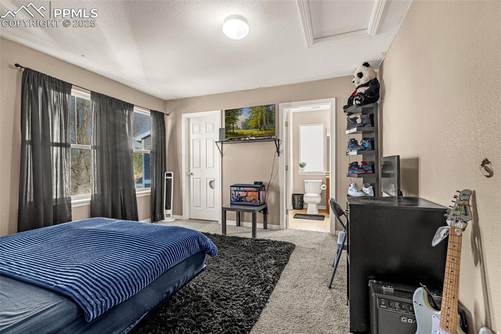 Carpeted bedroom featuring a textured ceiling and connected bathroom