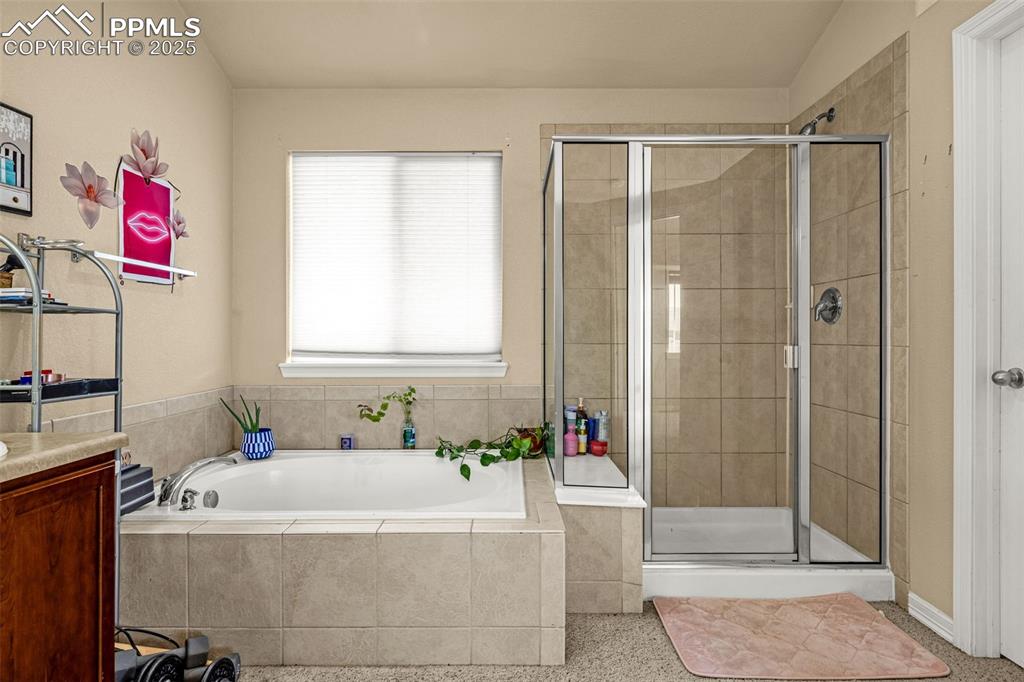 Full bathroom featuring a stall shower, a bath, and vanity