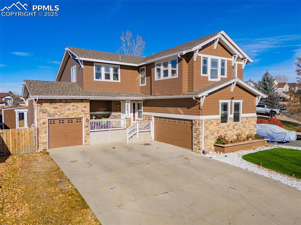 Craftsman inspired home featuring stone siding, driveway, a garage, and a shingled roof