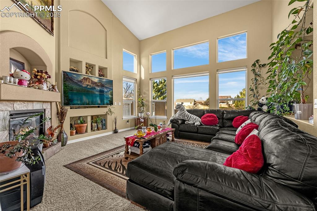 Carpeted living room with a high ceiling and a tile fireplace