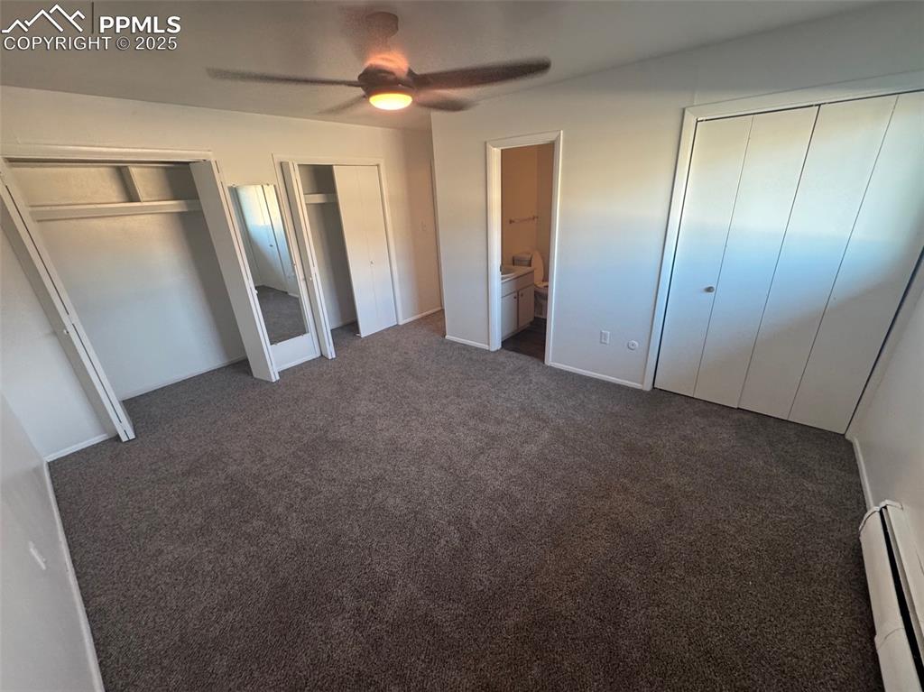 Unfurnished bedroom featuring multiple closets, a baseboard radiator, connected bathroom, and new carpet