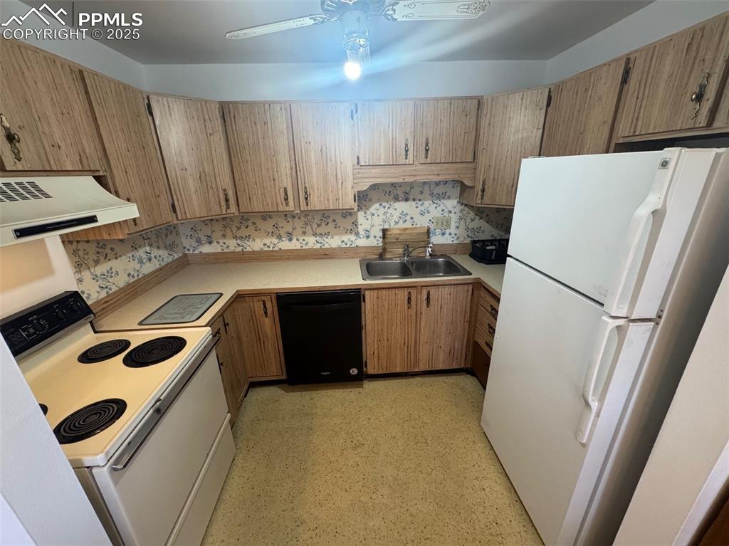 Kitchen with white appliances, light countertops, exhaust hood, a ceiling fan, and brown cabinets