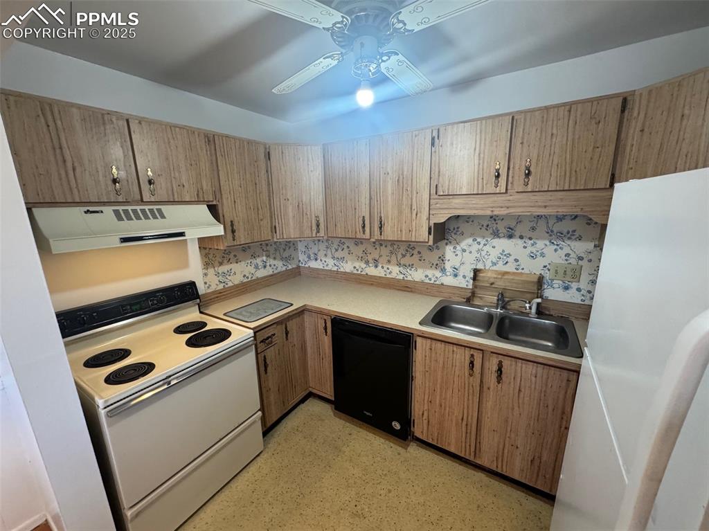 Kitchen featuring white appliances, light countertops, extractor fan, and ceiling fan