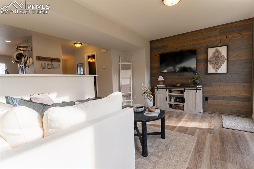 Living area with wood walls, light wood-style floors, and an accent wall