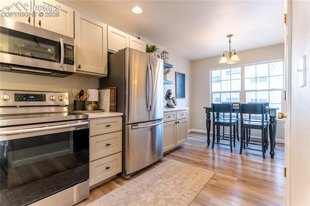 Kitchen with stainless steel appliances, light wood-style flooring, and white cabinets