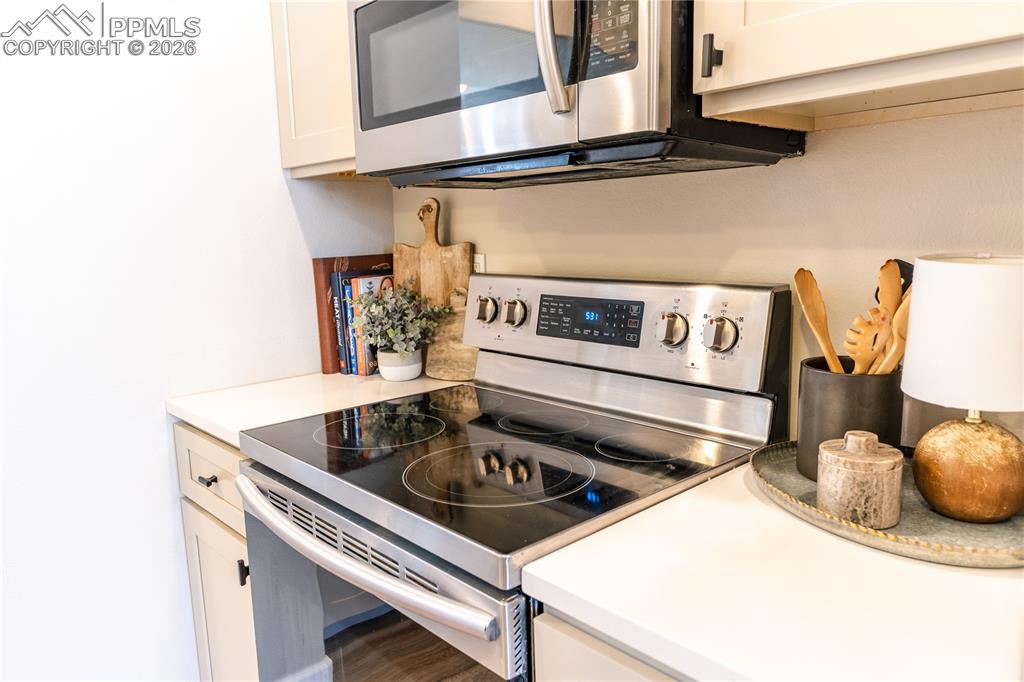 Kitchen featuring stainless steel appliances, light countertops, and white cabinetry