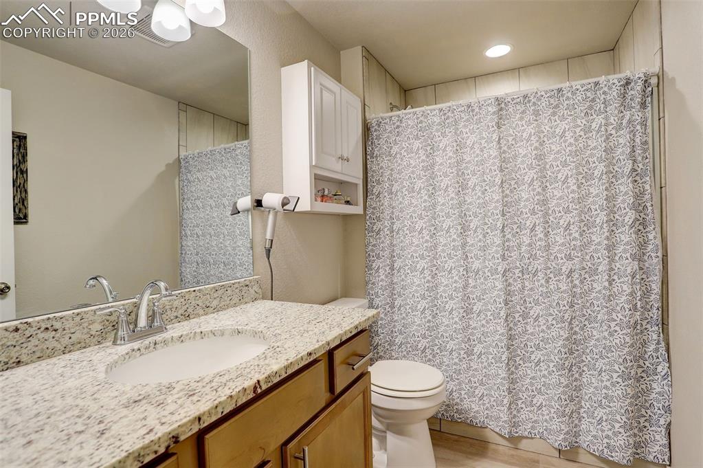 Lower Level; basement Full bathroom featuring stone vanity, shower/tub with tub to ceiling tile.