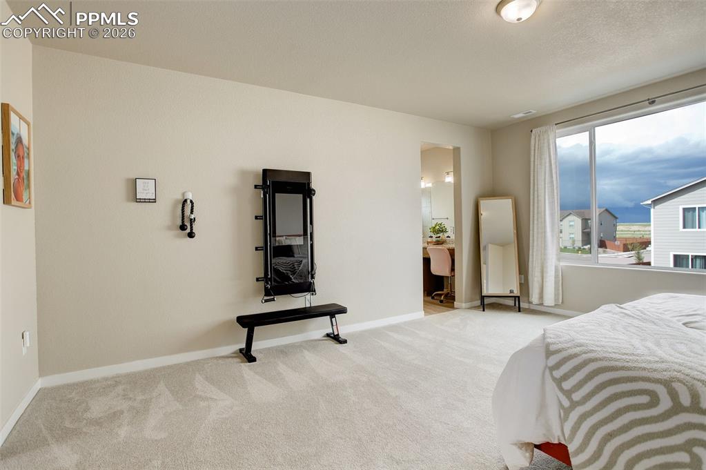 Carpeted bedroom featuring baseboards and connected bathroom