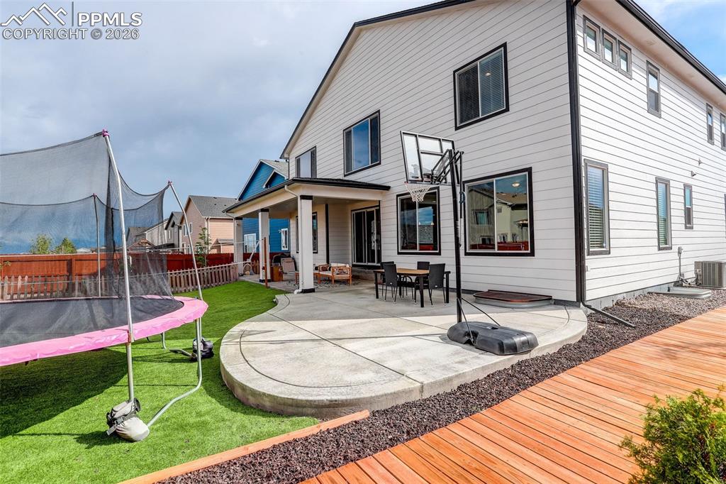 Rear view of property featuring a trampoline, a patio area, and a fenced backyard