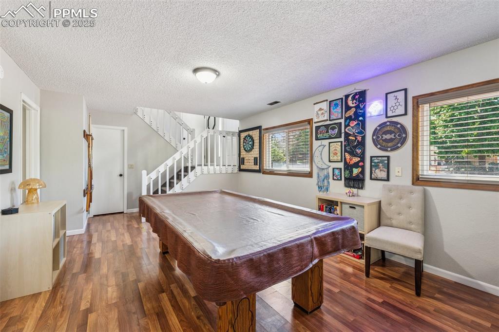 Rec room with a textured ceiling, billiards, and wood finished floors