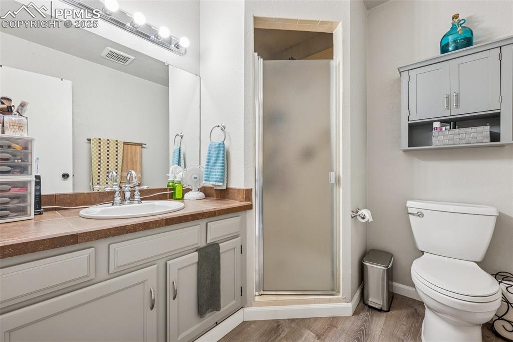 Bathroom with a shower stall, vanity, and wood finished floors