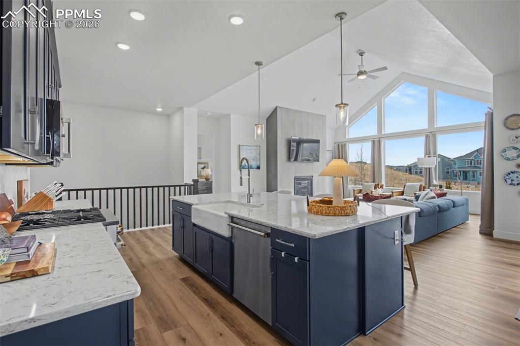 Kitchen featuring light stone countertops, open floor plan, dark wood-type flooring, a high ceiling, and ceiling fan