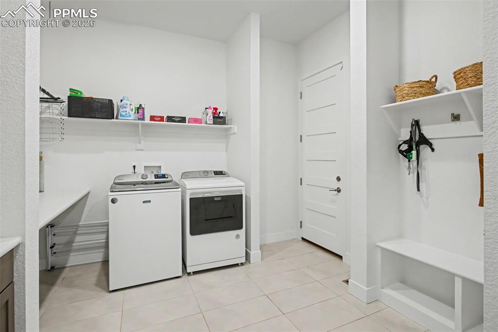 Laundry room featuring washing machine and clothes dryer and light tile patterned flooring