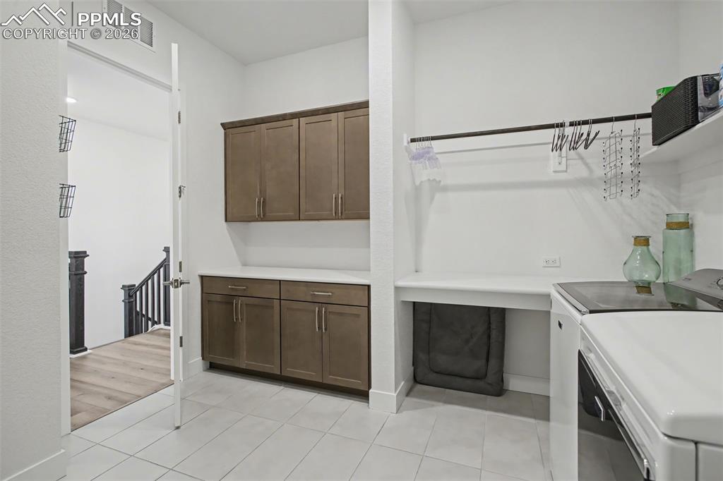 Laundry room featuring washer and dryer, light tile patterned floors, and cabinet space
