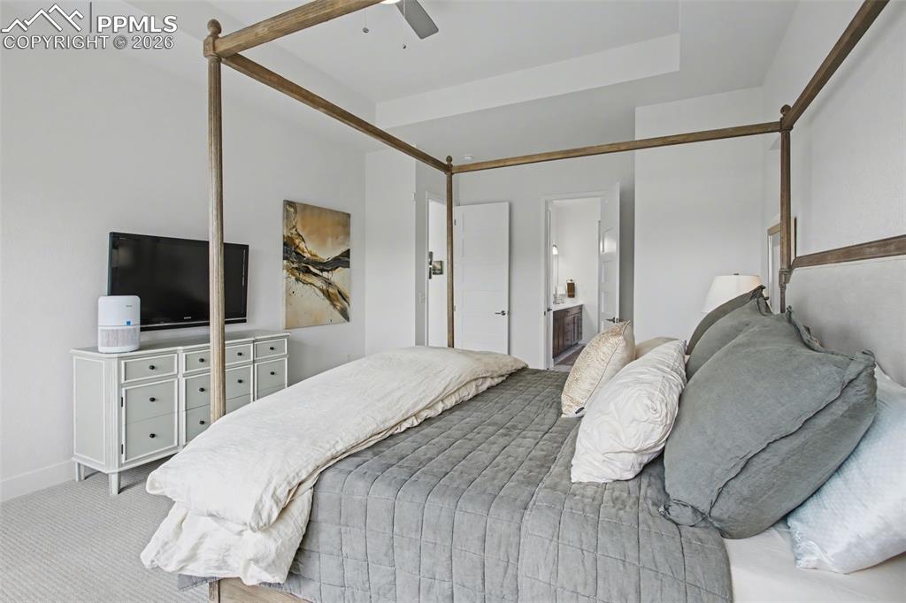 Carpeted bedroom featuring ceiling fan and connected bathroom