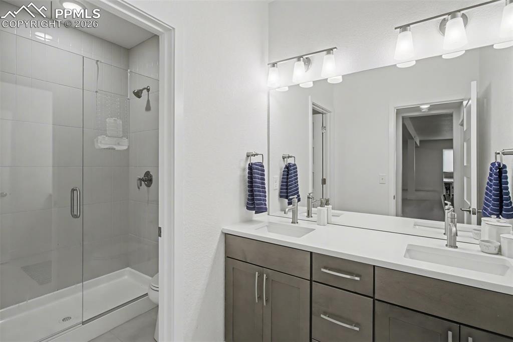 Full bath with double vanity and a shower stall