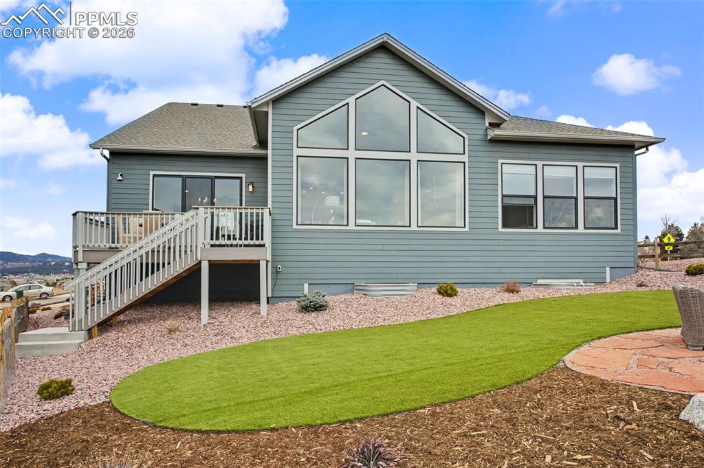 Rear view of house with roof with shingles and a wooden deck