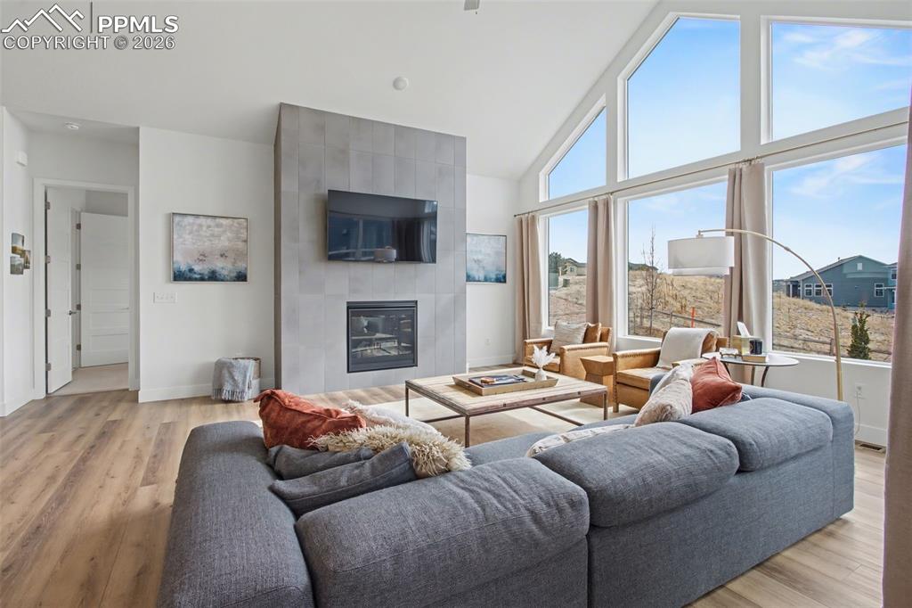 Living room featuring a tile fireplace, lofted ceiling, and light wood-style flooring