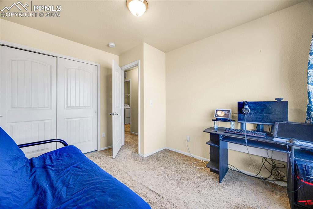 Bedroom with an office area, light carpet, and a closet