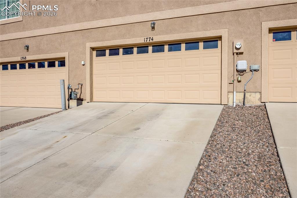 Wide concrete driveway with direct garage access and attractive rock border.