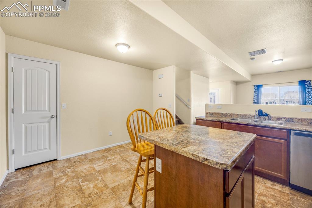 Bright kitchen view with island workspace and durable tile flooring throughout.
