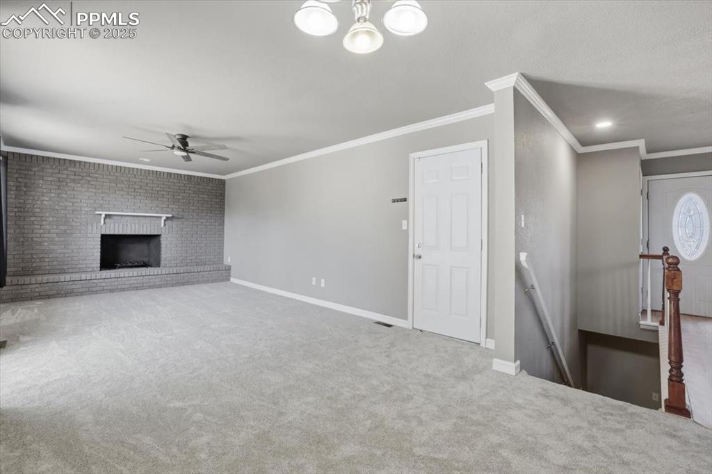 Unfurnished living room with carpet floors, crown molding, ceiling fan, a brick fireplace, and recessed lighting