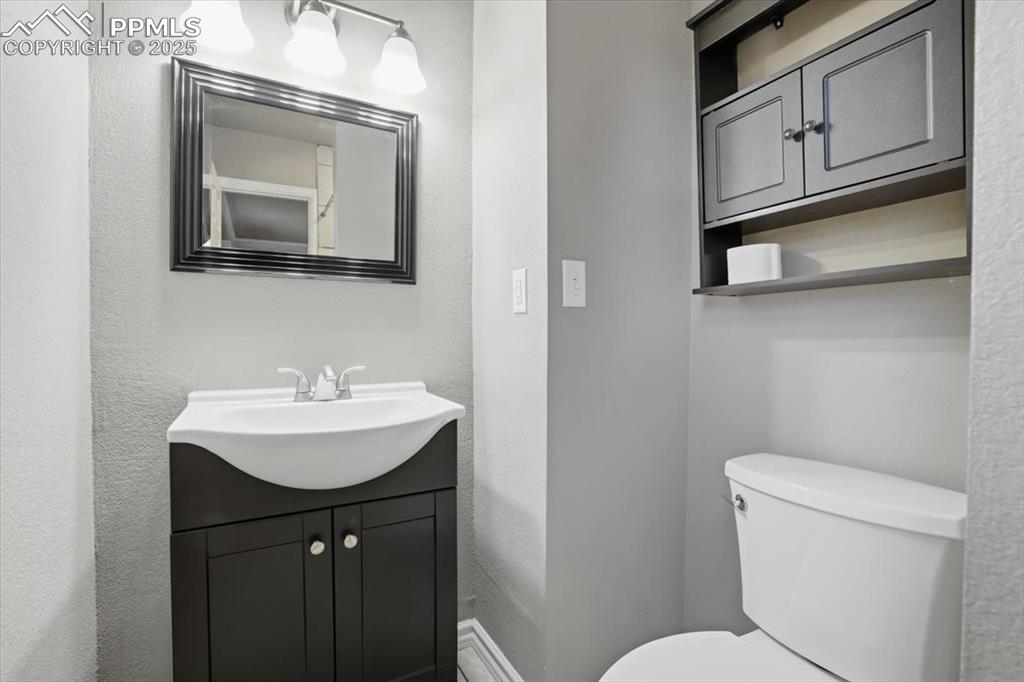 Half bath with a textured wall and vanity