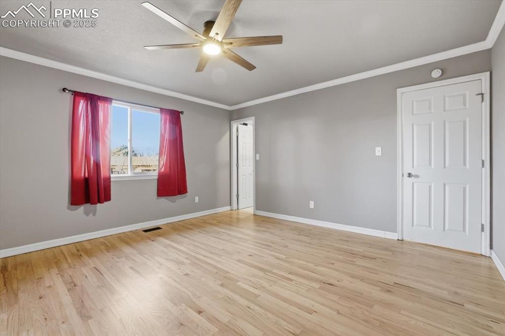 Spare room featuring ornamental molding, light wood finished floors, and a ceiling fan