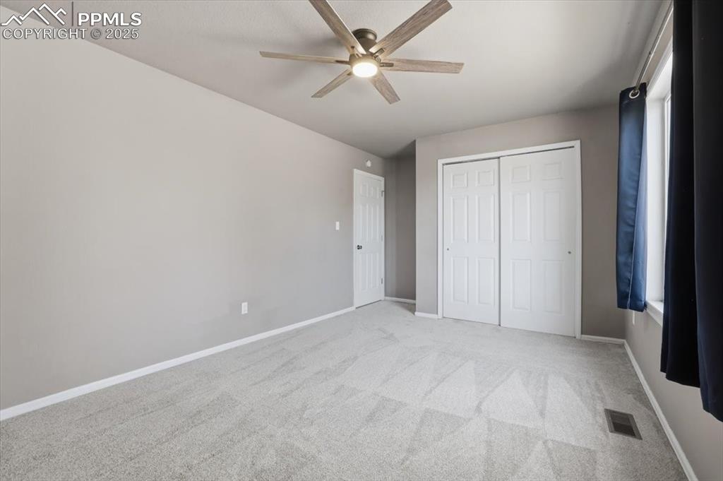 Unfurnished bedroom with light carpet, a ceiling fan, and a closet