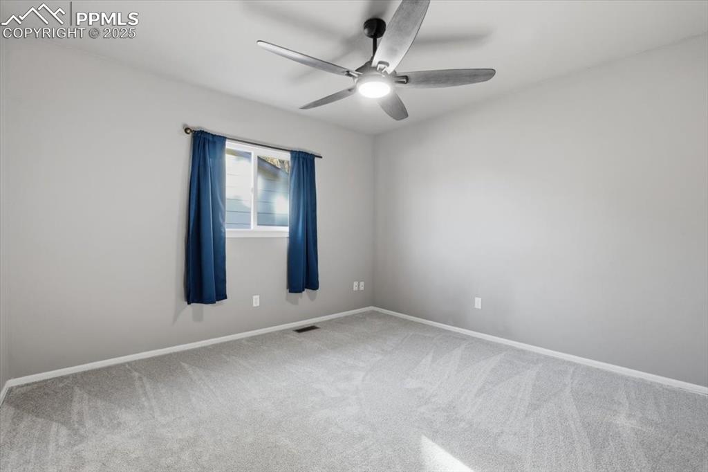Carpeted spare room featuring baseboards and a ceiling fan
