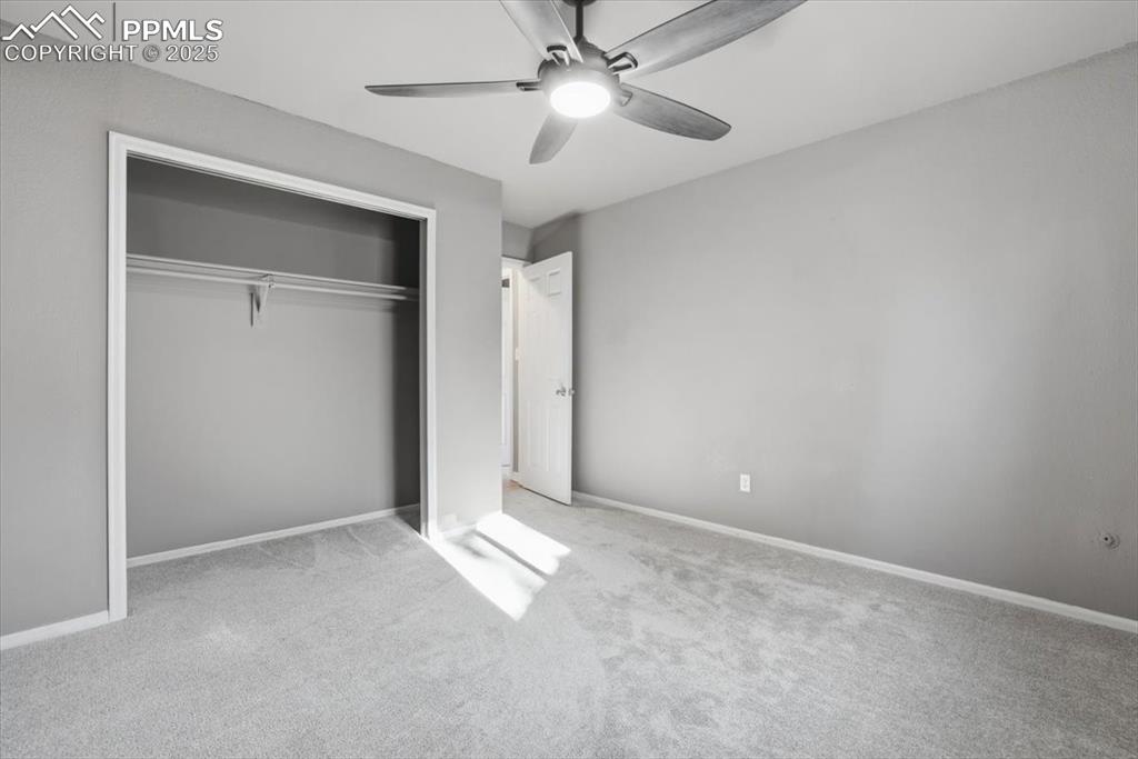 Unfurnished bedroom featuring carpet floors, ceiling fan, and a closet