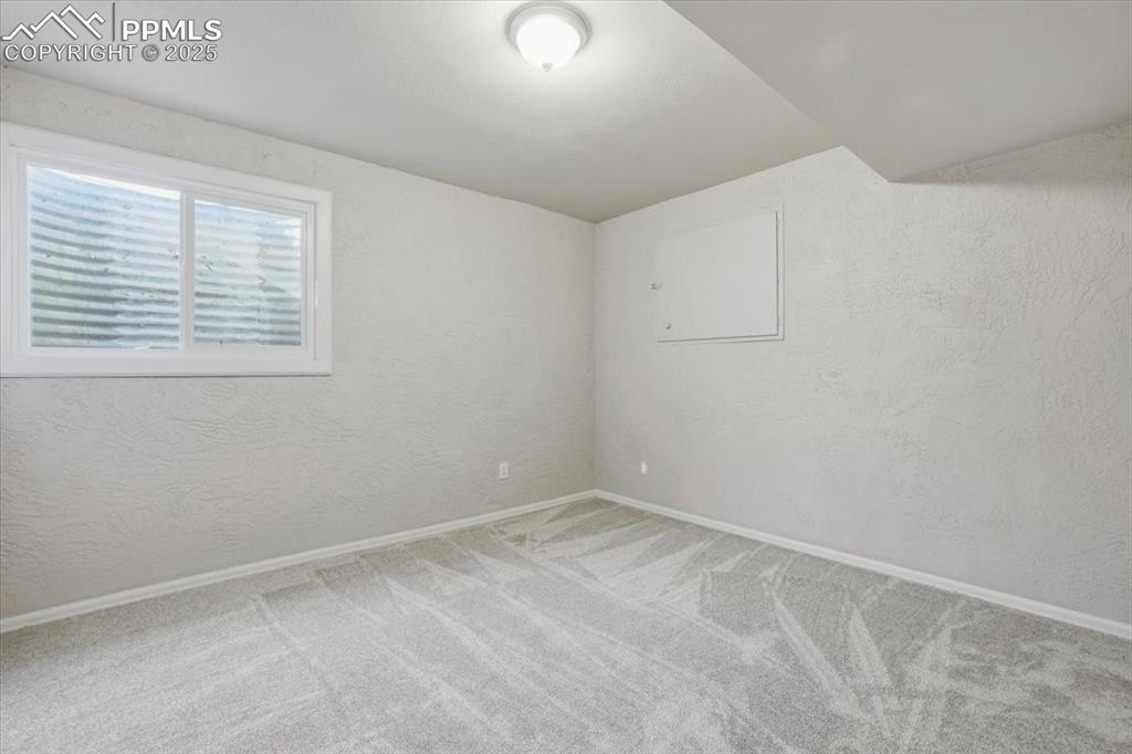 Carpeted spare room with a textured wall and baseboards