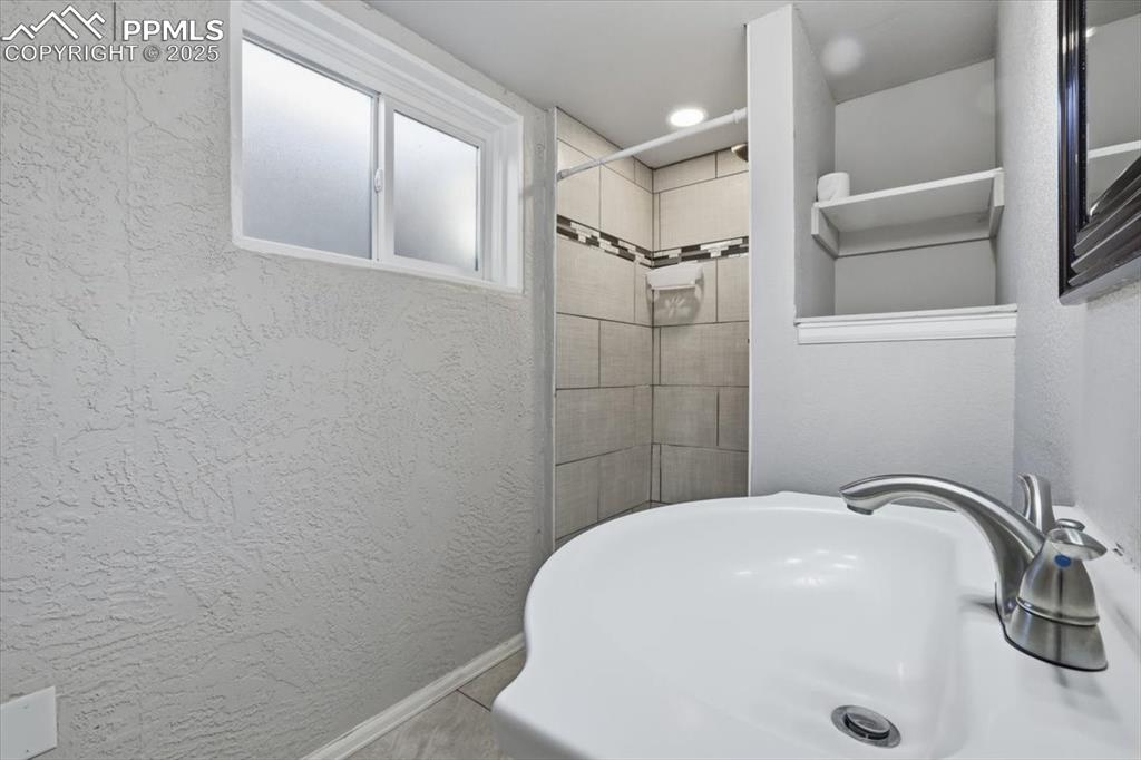 Bathroom featuring and tiled shower & storage