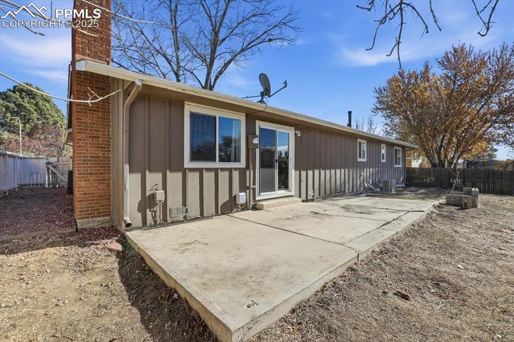 Back of property featuring a patio, board and batten siding, a chimney, and a fenced backyard