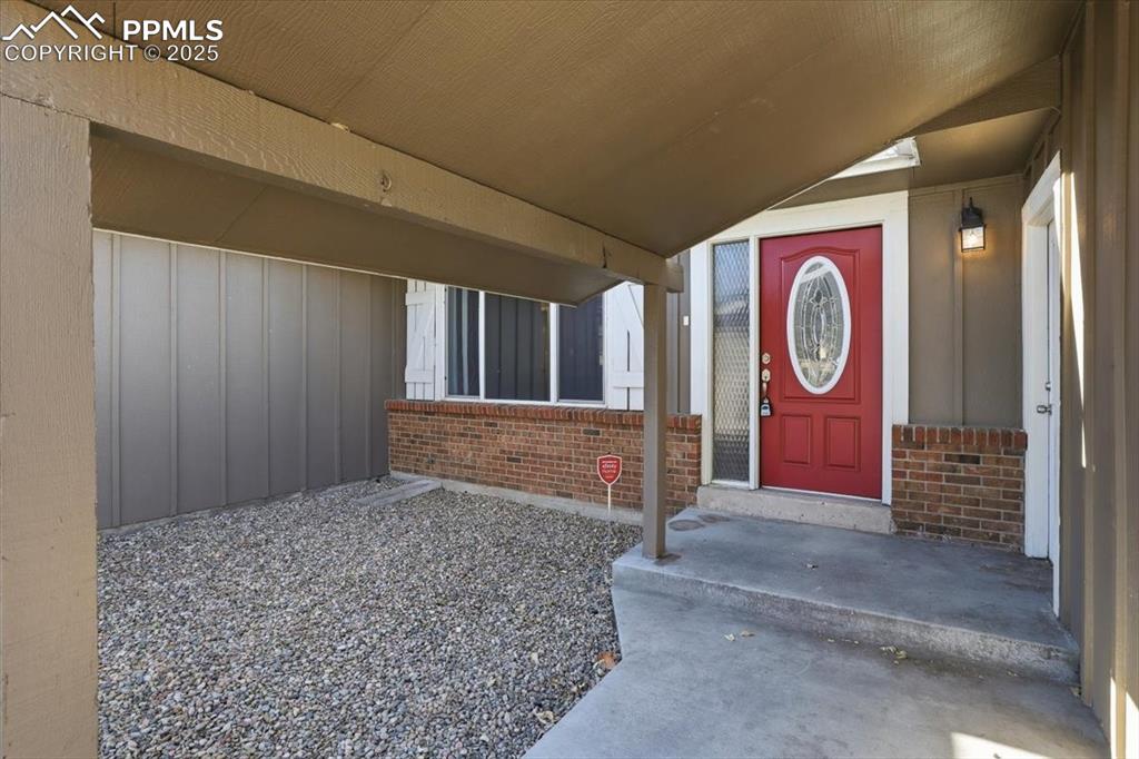 Doorway to property featuring covered porch and brick siding