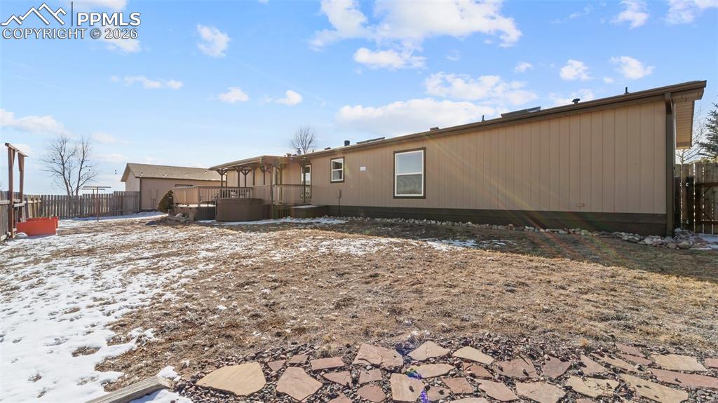 Snow covered back of property featuring a wooden deck