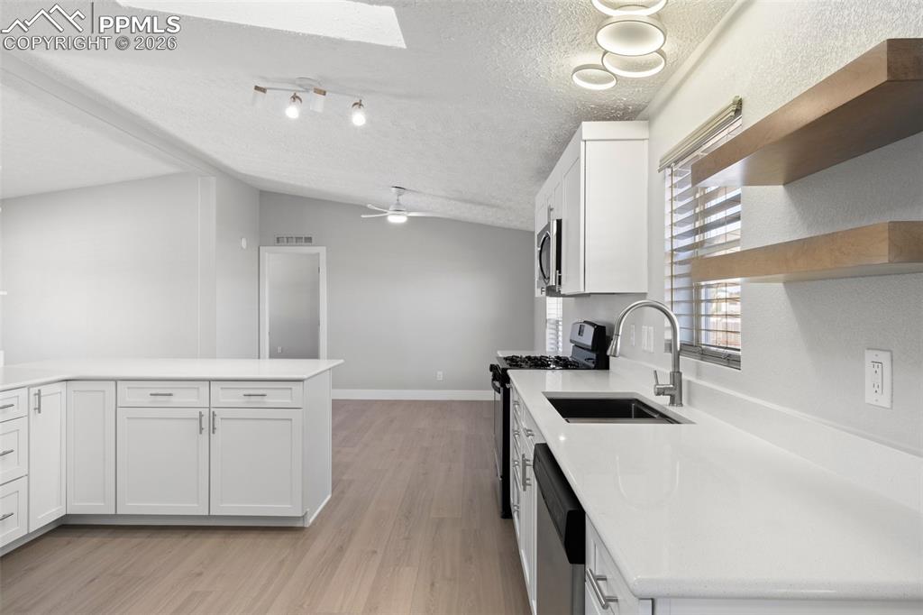 Kitchen with white cabinetry, appliances with stainless steel finishes, and sink