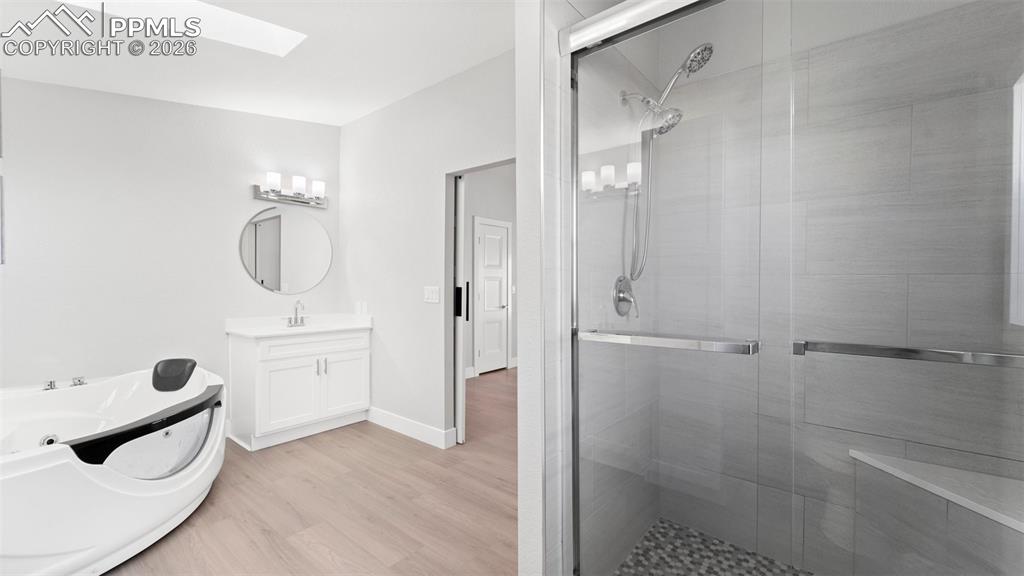 Bathroom with vanity, a skylight, wood-type flooring, and a shower with shower door