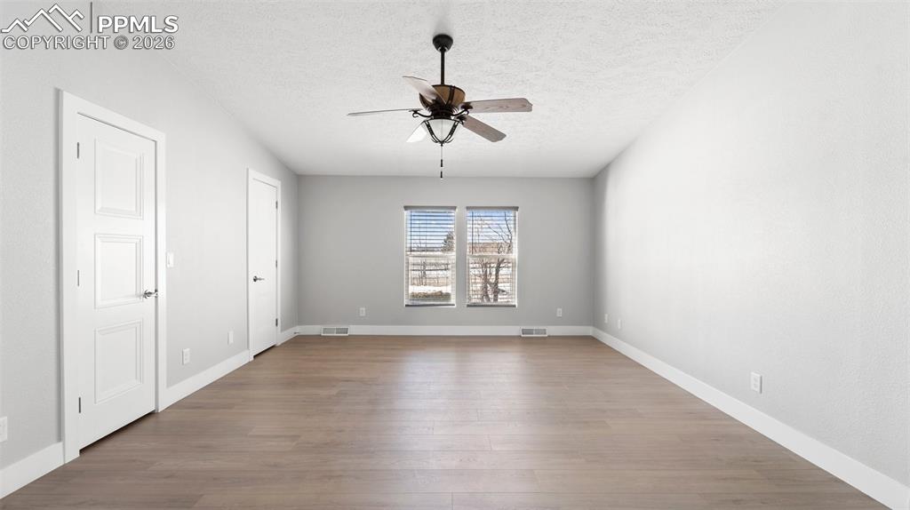 Empty room featuring hardwood / wood-style flooring, ceiling fan, and a textured ceiling