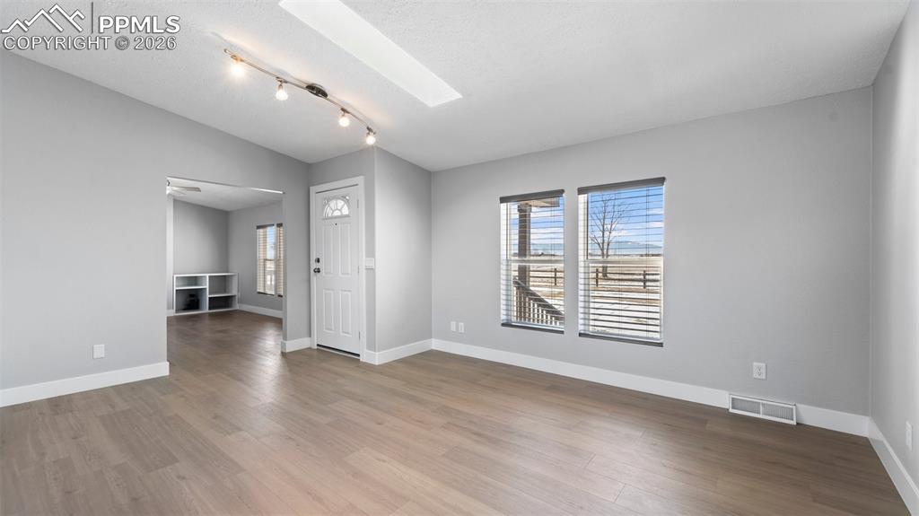 Spare room with vaulted ceiling with skylight, light hardwood / wood-style floors, and a textured ceiling