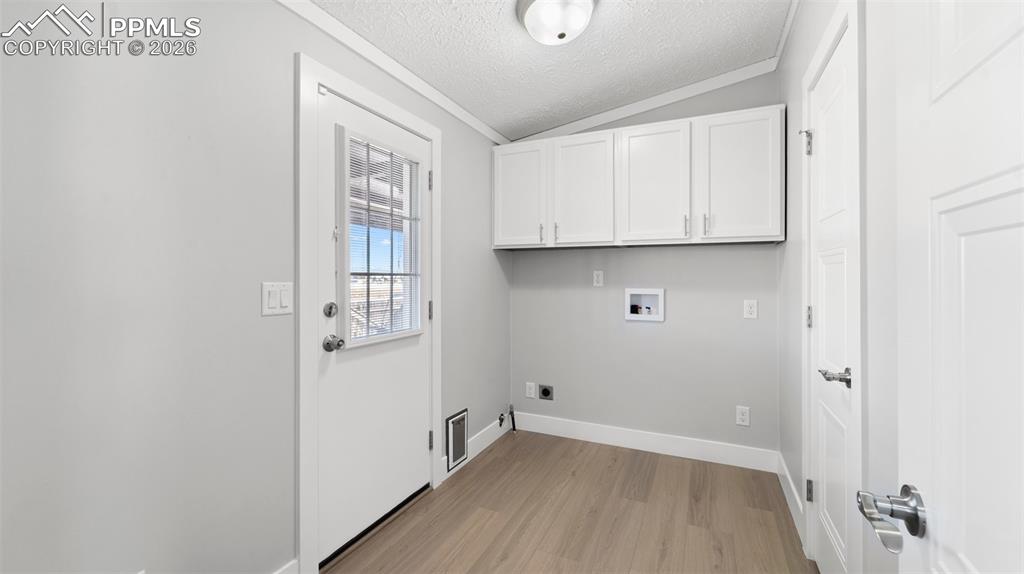 Laundry area with cabinets, light hardwood / wood-style floors, hookup for a washing machine, electric dryer hookup, and a textured ceiling