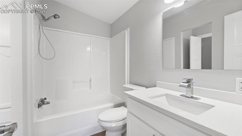 Full bathroom featuring vanity, lofted ceiling, washtub / shower combination, and toilet