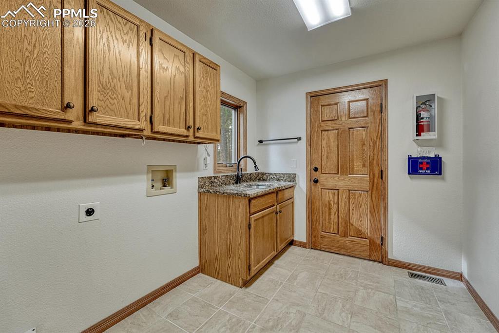 The Laundry Room features upper cabinetry, a sink, window, and access to an outdoor deck.